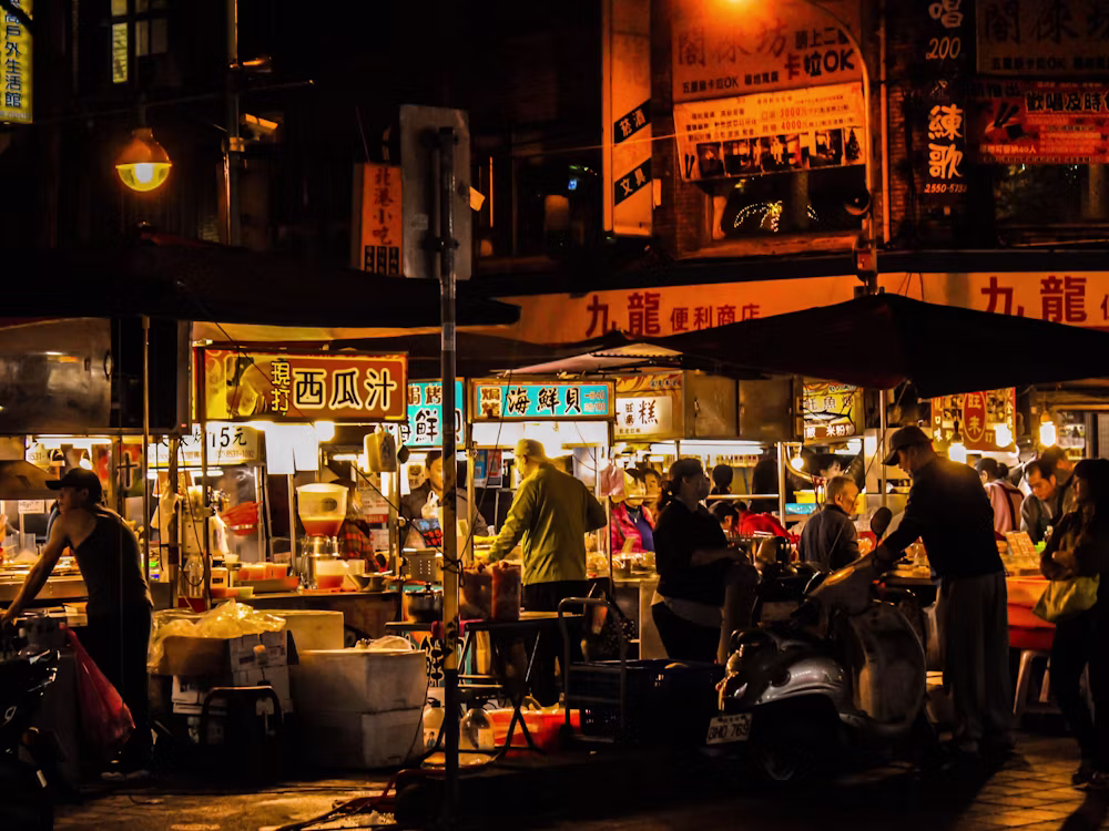 Glowing food stalls and crowds at a Taiwan night market after dark