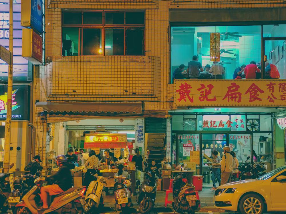 Warm evening street scene in Taiwan with scooters and a busy dumpling shop
